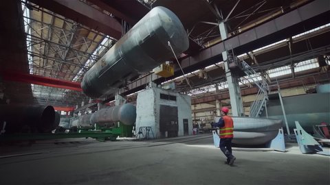 Worker Oversees Transportation Of Manufactured Railway Wagon. Worker Controls Process Of Wagon Transportation To Industrial Production Line. Worker Follows Wagon Transported By Heavy Crane Machine