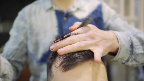 close up. the hairdresser makes a haircut for a brunette man with a scissors in a barbershop. professional services. beauty salon for men. cosmetics and products for scalp and hair care.