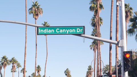 Palm trees and blue sky, Palm Springs resort city near Los Angeles, street road sign, semaphore traffic lights on a crossroad. California desert valley summer road trip on car, travel USA. Indian Canyon