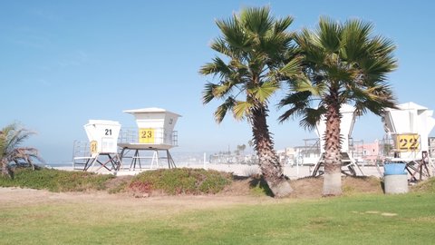 Lifeguard stand and palm tree, life guard tower for surfing on California beach. Summer pacific ocean in USA aesthetic. Iconic rescue baywatch station, coast lifesavers wachtower hut or house by sea.