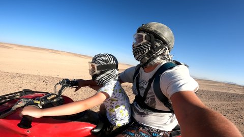 A happy family is having fun during the summer holidays on quad bikes in the desert. Quad bike ride. Tourists ride quad bikes.
