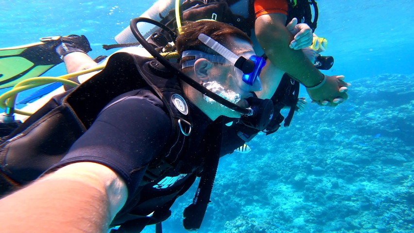 Three men scuba-dived into the sea in search of a coral reef. Scuba divers in the sea. Scuba divers under water. | Shutterstock HD Video #1087699175