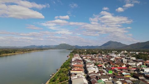 Aerial footage descending and revealing the rooftops of the Walking Street then the Mekong River to the left and Laos, Chiang Khan, Loei in Thailand.