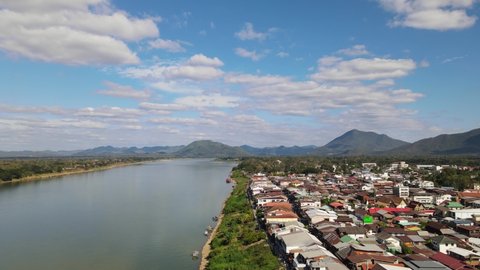 Ascending aerial footage of Chiang Khan in Loei, revealing mountains and a lovely sky in Thailand, Laos across Mekong River on the left.