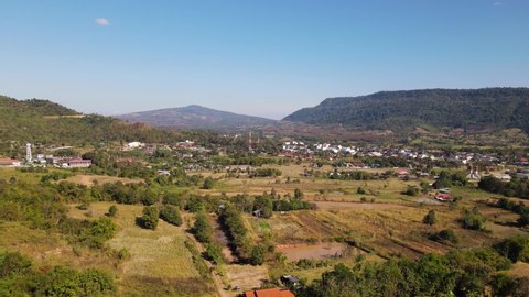 Reverse aerial footage of this provincial landscape revealing a town and farmlands, Wat Somdet Phu Ruea, Ming Mueang, Loei in Thailand.