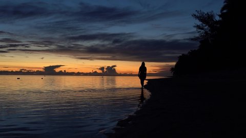 Beautiful sunset on the southern shore og Rarotonga island with a girl barefoot in the lagoon