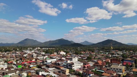 Aerial footage towards the horizon with mountains and beautiful sky with cloud flying over rooftops at the Walking Street in Chiang Khan, Loei, Thailand.