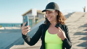 Middle age woman wearing sportswear having video call at street