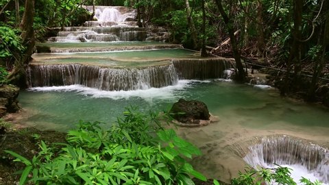 Majestic Waterfall In Tropical Forest. Scenic nature of beautiful waterfall and emerald pool of fresh water lake in wild jungle forest environment.
