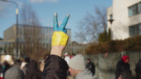 WARSAW, POLAND - FEBRUARY 27 2022: Hand In The Colors Of The Flag Of Ukraine Showing A Victory Gesture, Demonstration, Protest Against The Russian War Invasion In Ukraine. Ukrainian Flag, Protesters