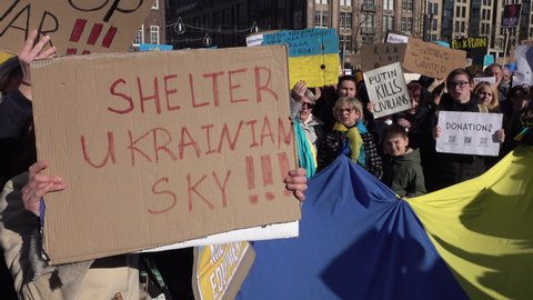 AMSTERDAM, NETHERLANDS – FEBRUARY 27 2022: Protesters hold signs asking to 'shelter Ukrainian sky', asking NATO for air support (no fly zone) against Russia's invasion. War in Europe.