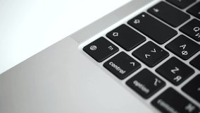 Hand pressing the globe key on modern laptop keyboard close-up slow motion 