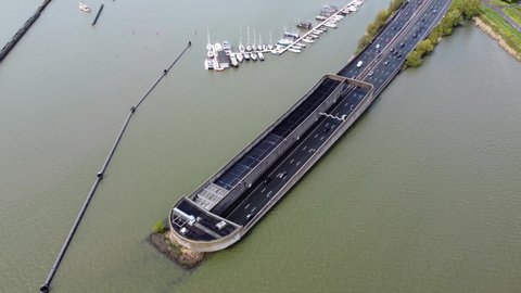 Aerial drone view moving over road tunnel going underwater traffic moving in both ways located in Holland which is well known for its innovative water management and infrastructure solutions 4k