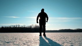 Silhouette of a man walking into the distance through the snow during sunset. A loner walks across a large meadow of snow. Failure and loneliness. - Powered by Shutterstock - Get 15% off with code: PIKWIZARD15