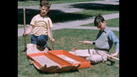 1950s: A woman steps into a room, two boys holding badminton rackets run up and speak to her. Two boys unwrap a box on a patch of grass. They pull out the disassembled pieces of a badminton net.