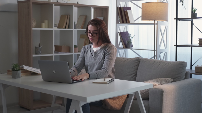 Finish work. Exhausted woman. Warming exercises. Tired lady feeling tense neck massaging it after closing laptop sitting desk in light room interior.