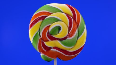 rotation of a spiral fruit lollipop on a blue background. Caramel lollipops. Sweets for children.macro.childhood concept.