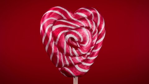 Rotation of lollipop in heart shape on red background.Candy on stick.Saint Valentine's Day. The 14th of February.Women's day.love concept.macro