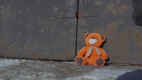 equipped man in protective anti chemical clothing and gas mask opens refuge door, tilts and lifts teddy bear and leaves back, closing door behind him, view from below