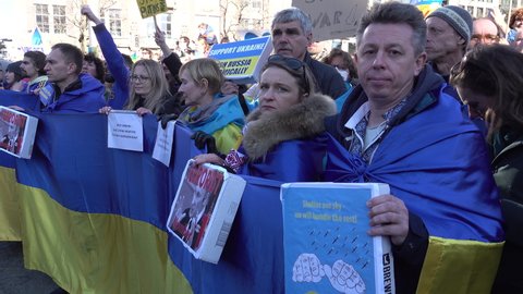 AMSTERDAM, NETHERLANDS – FEBRUARY 27 2022: Ukrainian diaspora hold huge flags during anti-war demonstration and support rally (in Amsterdam), after Russia's invasion of the country