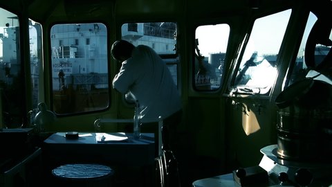 Buenos Aires, Argentina - March 2020: Man Carefully cleaning the Interior of a Wheelhouse with a Rag on a Tugboat Docked in the Port of Buenos Aires, Argentina.  
