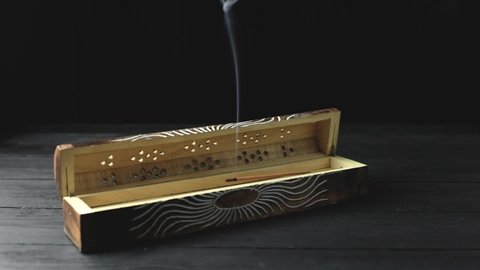 Closed incense holders smoking on black background