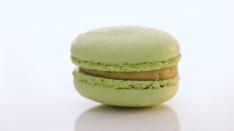 Green macaron pastries rotate on white background. Colorful cake macaroons isolated on abstract background. Traditional French multicolored macaroon. Food concept.