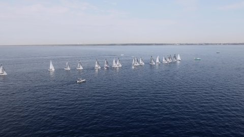 Sailing yachts lined up in the sea during a sailing regatta and cast shadows