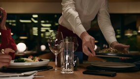 Restaurant waiter putting plates on fancy cafe table. Unknown romantic couple enjoying serving in modern interior bar. Two lovers waiting italian food on evening date close up. Tasty dining concept. - Powered by Shutterstock - Get 15% off with code: PIKWIZARD15