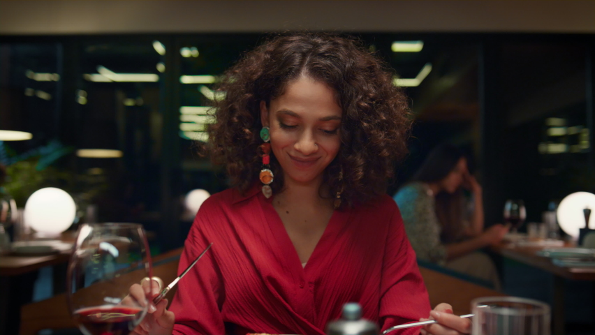 African american girl eating tasty meal in fine dining place. Gorgeous woman enjoying dinner in italian fancy restaurant. Young pretty lady looking camera on date concept. Romantic tasty meal concept. Royalty-Free Stock Footage #1087731407