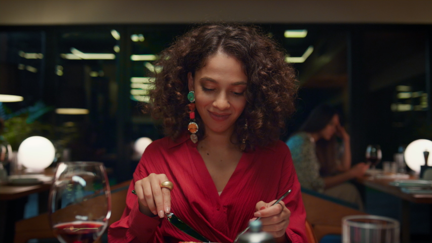 African american girl eating tasty meal in fine dining place. Gorgeous woman enjoying dinner in italian fancy restaurant. Young pretty lady looking camera on date concept. Romantic tasty meal concept.