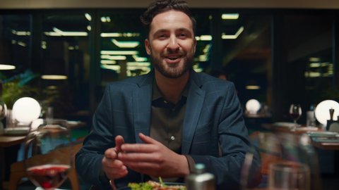 Emotional man talking on date dinner. Handsome guy gesturing hands on restaurant table. Pov person having lunch with happy boyfriend in fancy cafe. Businessman smiling in eating place. Dining concept.