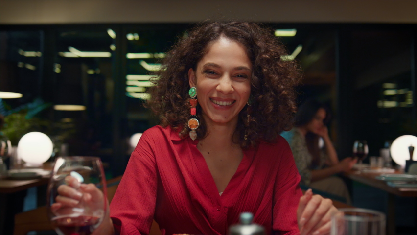 Laughing woman looking camera on romantic dinner date in fancy restaurant. Attractive african american girl smiling at cafe table. Young lady wearing beautiful dress in night bar. Fine dining concept. Royalty-Free Stock Footage #1087731458