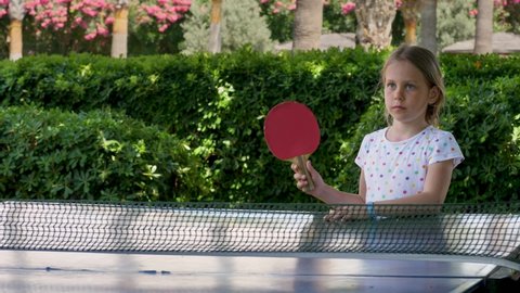 Youth schoolgirl play table tennis. Child player hit lightweight ping-pong ball back and forth across hard table divided by tennis net use small red rackets. 