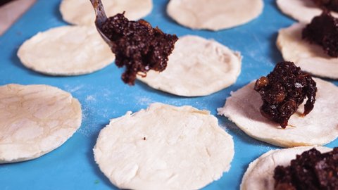 Women's hands are sculpting gomentashi cookies for the Purim holiday with poppy seeds