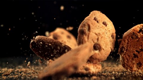 Cookies with pieces of chocolate fall on the table and crumble. On a black background. Filmed is slow motion 1000 fps.High quality FullHD footage