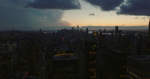 Aerial panoramic view of cityscape at dusk. Fly above city after sunset. High rise buildings and downtown skyscrapers. Manhattan, New York City, USA