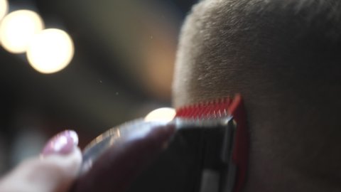 Professional barber doing haircut for customer using electric machine and comb. Close up. slow motion