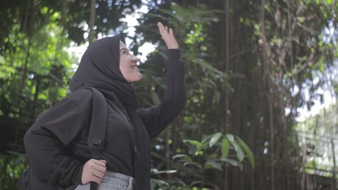 beautiful girl in black jacket and hijab is enjoying the view in the forest