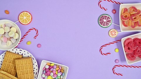 6k Sweets, candies and lollipops arrangement appear on pastel purple background. Stop motion flat lay	