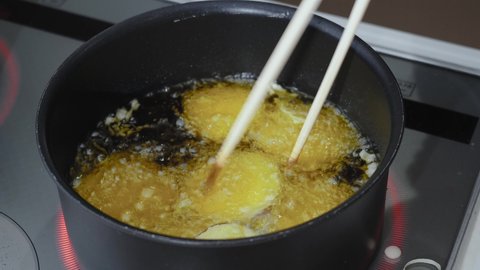 A woman's hand frying sweet potato tempura