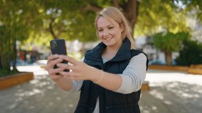 Young blonde woman smiling confident having video call at park