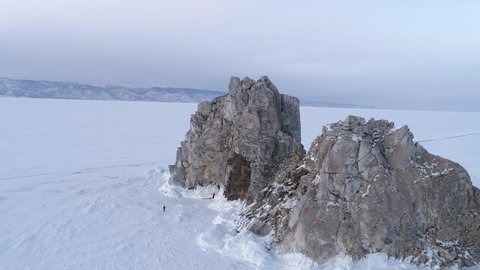 Aerial orbital shot of Shamanka rock and on Olkhon. Beautiful view on frozen Baikal. Panoramic winter landscape. Popular touristic destination