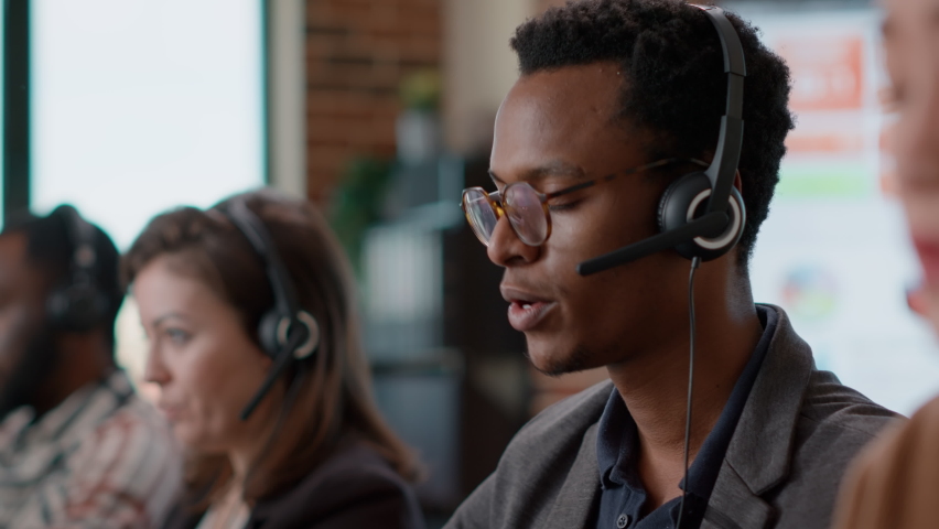 African american worker having conversation on headset with client, offering telemarketing assistance at call center. Man with headphones and microphone working at customer service. Close up. - Powered by Shutterstock - Get 15% off with code: PIKWIZARD15