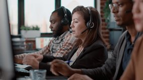 Young woman using audio headset and computer at call center job, offering helpline assistance to people. Female consultant talking to clients at customer care service, helping with telemarketing. - Powered by Shutterstock - Get 15% off with code: PIKWIZARD15