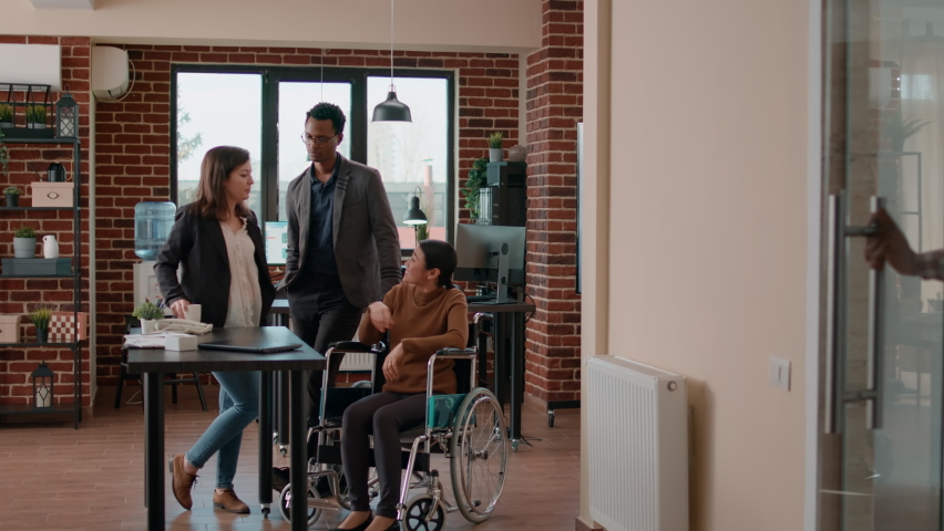 Business people meeting in office to have fun conversation, feeling cheerful and laughing together. Young workers enjoying break and collaborating in disability friendly office. Royalty-Free Stock Footage #1087753247