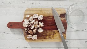 Time lapse. Flat lay. Cutting organic bella mushrooms on a wood cutting board.