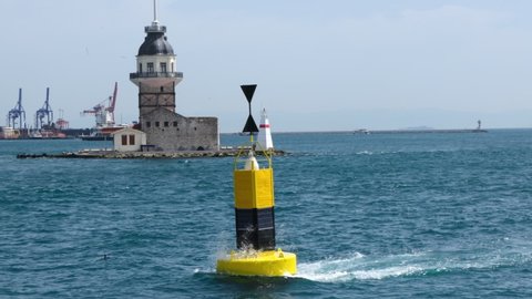 A yellow buoy and The Maidens Tower in the background in Istanbul. Strong flow is visible on the sea surface.