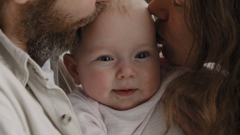 Close-up baby face happy child kid expression little girl small boy toddler infant laughing smiling looking at camera loving caring parents kissing newborn on cheeks adoption childcare family bonding