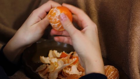 The girl cleans the tangerine. Hands clean tangerine. Video